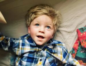 A head and shoulder photograph of a child lying on a soft mattress, eyes pointed upwards.